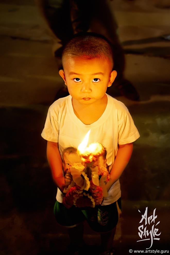 Baby holding his offering at That Luang festival, Wat Inpeng, Vientiane, Laos.